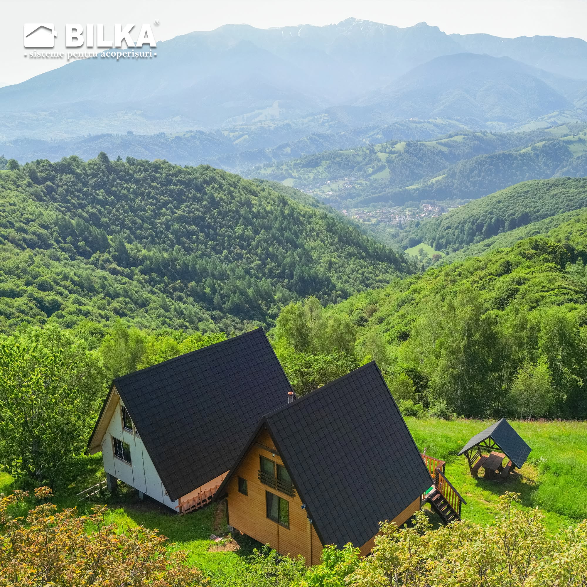 Cabane cu acoperișuri antracit într-un peisaj montan verde